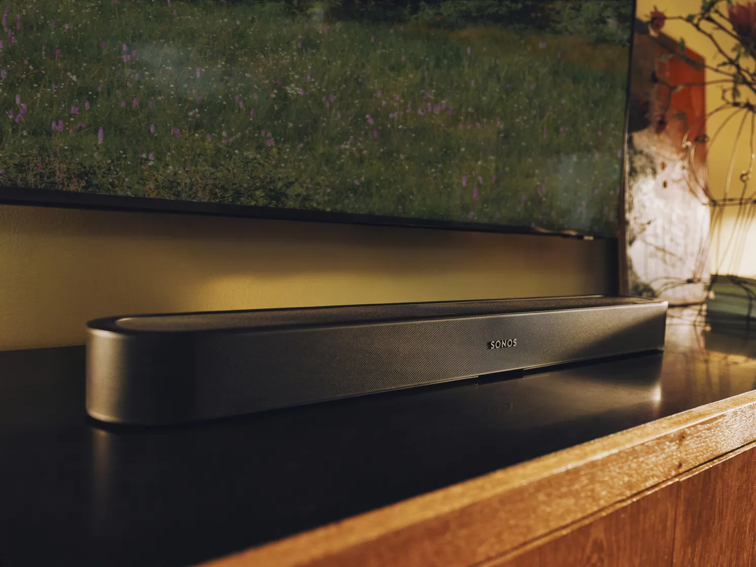 Zwarte Sonos Beam Ultra op een houten tv-meubel, van dichtbij